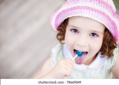 Little kid enjoying a lollypop while staring at camera from below