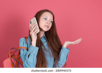 Little Kid Girl 13 Years Old In Blue Denim Jacket Isolated On Pink Background Schoolgirl With Backpack With Mobile Phone Have No Clue, Shrugging Shoulders