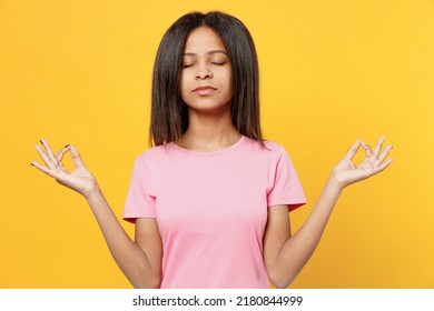 Little Kid Girl Of African American Ethnicity 12-13 Years Old In Pink T-shirt Spread Hands In Yoga Om Aum Gesture Relax Meditate Try Calm Down Isolated On Plain Yellow Background. Childhood Concept