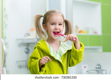 Little Kid Girl Brushing Teeth In Bathroom