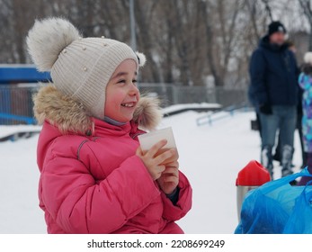 Little Kid Girl With A Cup Of Warm Cocoa Outdoors For Christmas. Child On A Walk In The City Park. Family Winter Vacation. An Alternative To Computer Games. A Girl In A Pink Jacket Drinks Hot Tea In 