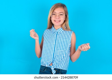 Little Kid Girl With Glasses Wearing Plaid Shirt Over Blue Background, Making Money Gesture.