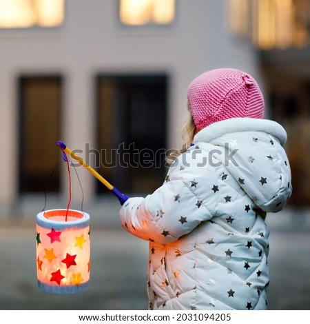 Little kid girl holding selfmade lanterns with candle for St. Martin procession. Healthy cute toddler child happy about children and family parade in kindergarten. German tradition Martinsumzug