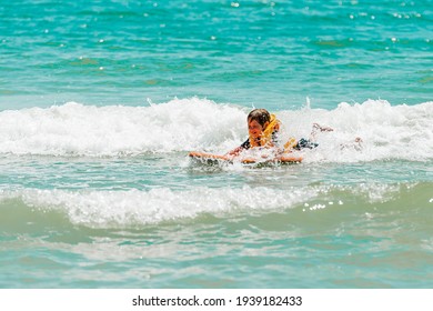Little kid girl learning surf in sea. Little kid surfer with surfer board on sea beach on family vacation.. Empty wild beach for safe travel. Summer tours.