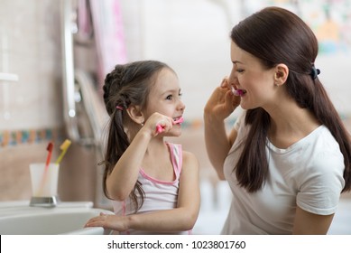 Little Kid Girl And Mom Brushing Teeth In Bathroom