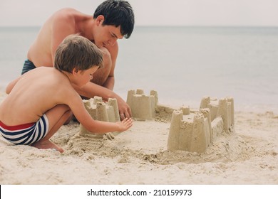 little kid and his father building sandcastle - Powered by Shutterstock