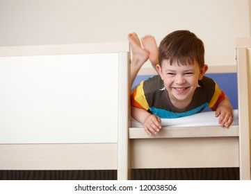 Little Kid Laughing On Top Of Bunk Bed, Laying On Front.