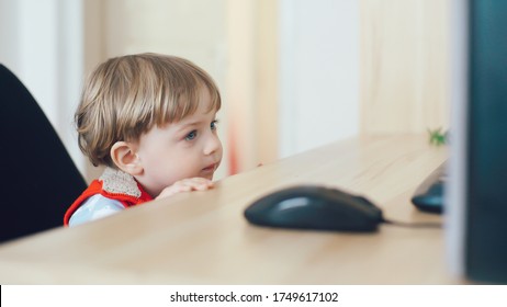 Сute Little Kid Licks The Table While Watching TV. Young Boy With Blue Eyes Watch Television On Living Room. Child Watching TV, Close Up Face Of Little Boy, Kid Eyes.