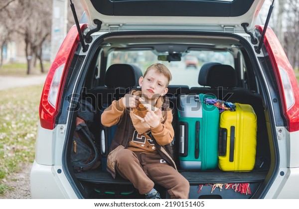 little kid looking into paper bag with candies\
sitting in car trunk full of\
bags.