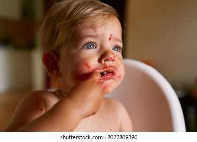 Little Kid With Messy Face Holds Finger In Mouth