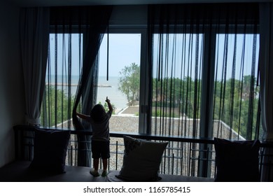 Little Kid Open Black Curtain (mosquito Net Fabric) To See Outside The Window.