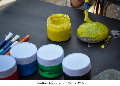 A Little Kid Painting Rock Yellow