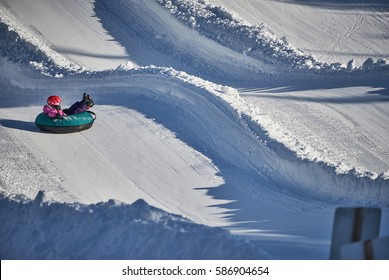 A Little Kid With A Pink Helmet Enjoying Tubing Down The Wavy Snow Track At Lake Louise Ski Resort
