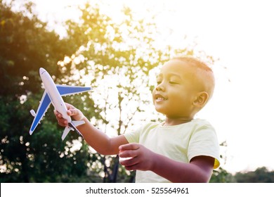 Little Kid Playing With Airplane Toy In Green Park