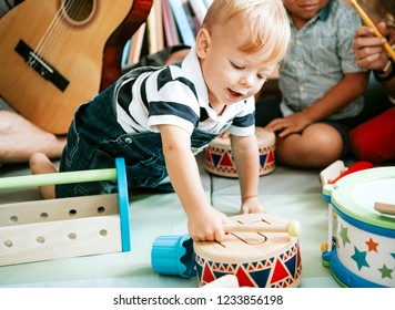 Little Kid Playing With A Wooden Drum Set