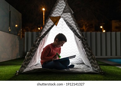 Little kid reading a book on a indian tent at night - Powered by Shutterstock