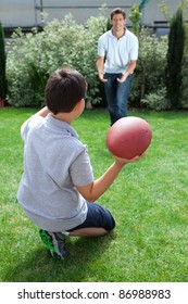 Little Kid Throwing Football To His Father In Backyard