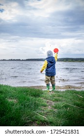 Little Kid Throwing Rocks In Lake. Rubber Boots