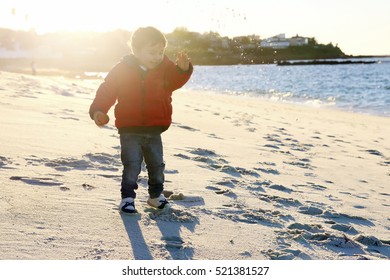 Little Kid Throwing Sand In The Beach In Autumn