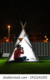 Little kid using a binoculars on a indian tent at night