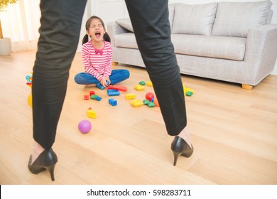 little kids girl sad crying due to her mad crazy business woman mother censure her behavior with messy living room toys are every at home.