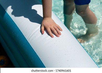 A Little Kids Hand Leans On The Inflatable Kiddie Pool In His Back Yard. 