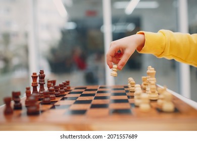 Little kids playing chess at kindergarten or elementary school. Hand holds chess figure close up.