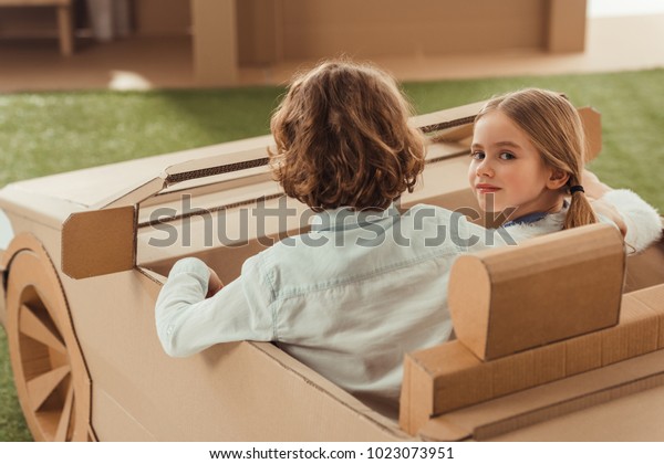 little kids riding cardboard\
car