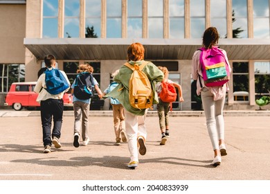 Little kids schoolchildren pupils students running hurrying to the school building for classes lessons from to the school bus. Welcome back to school. The new academic semester year start