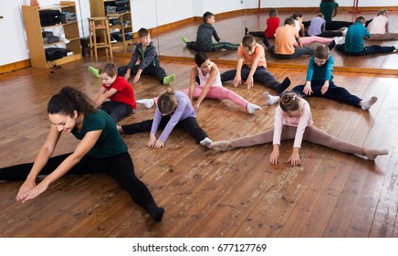 Little Kids Stretching With Female Teacher In Dance Class