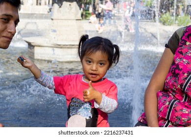 Little Latin Girl Giving Food To Her Dad And Making A Like Sign With Her Hand