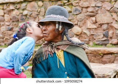 Little latin girl kissing her native american grand grandmother.