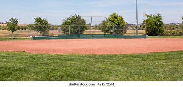 Little League Baseball Field With Green Grass, Brown Dirt And No People