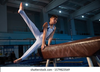 Little male gymnast training in gym, flexible and active. Caucasian fit little boy, athlete in white sportswear practicing in exercises for strength, balance. Movement, action, motion, dynamic concept