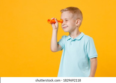 Little Male Kid Boy 5-6 Years Old Wearing Stylish Blue Turquoise T-shirt Polo Looking Far Away Distance Through Toy Spyglass Telescope Isolated On Yellow Color Wall Background, Child Studio Portrait