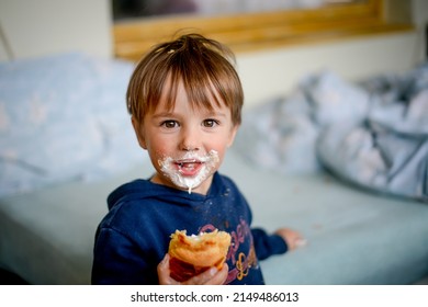 Little messy boy with dirty face while eating sweets. Funny happy kid portrait. Tasty food. Child is eating croissant - Powered by Shutterstock