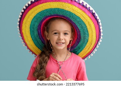 Little Mexican girl with colorful sombrero hat on blue background