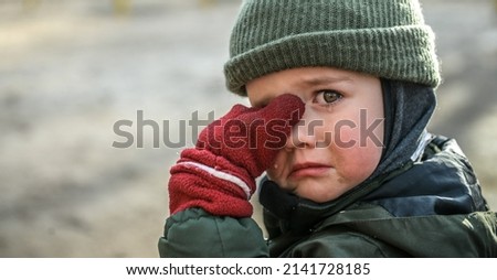 Little migrant child cry. Portrait of kid boy wipes tears. Evacuation children. War Ukraine