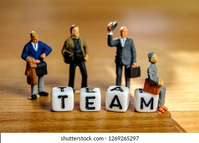 little miniature figurines with little dices forming specific word as a part of team meeting collection pictures dedicated to one part of its time table on wooden background - Powered by Shutterstock