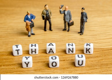 little miniature figurines with little dices forming specific word thank you as a part of team meeting collection pictures dedicated to one part of its time table on wooden background - Powered by Shutterstock