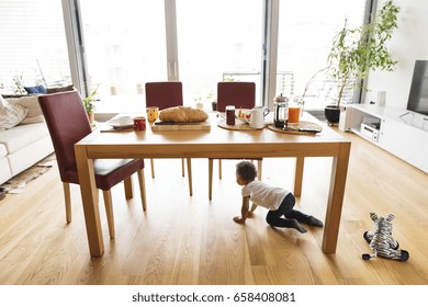 Little Mixed-race Girl At Home Under The Kitchen Table.