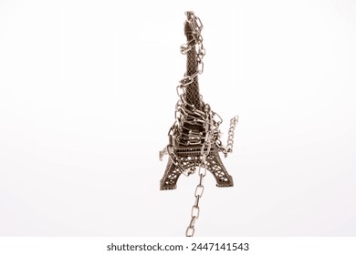 Little model Eiffel Tower  in chains on a white background