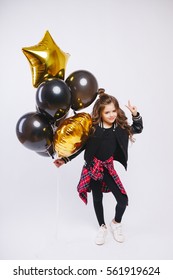 Little modern hipster girl in fashion clothes hold balloons and make peace by her hand