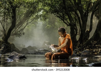 Little monk washing alms bowl at river, Nong Khai, Thailand. - Powered by Shutterstock