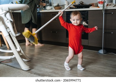 Little Mothers Helper. Cute Toddler Baby Girl With Mop Help Her Mom Do Housework In Kitchen. Cute Little Baby Girl Play With Mop And Makes Cleaning The House