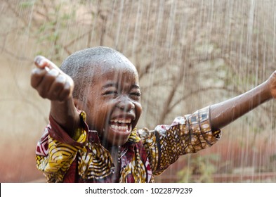 Little Native African Boy Standing Outdoors Under the Rain (Water for Africa Symbol)