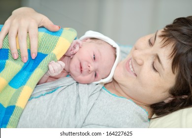 Little Newborn Baby In The Arms Of Mother. The Baby After Birth. Birth In A Hospital