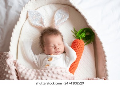 Little newborn baby sleeping in a bassinet. Baby sleeping in a Moses basket, wearing sparkly bunny ears and holding a carrot. 