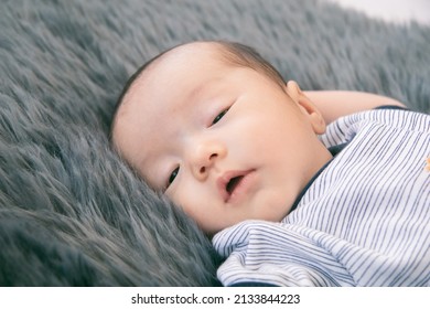 Little Newborn Baby Sleeping On Gray Fur Bed With Happy, Adorable Infant Wear Blue Casual Clothes Lying In Bedroom With Feel Safe. Asian Toddler Sleep On His Back Relaxing On Bed. Nursery For Children