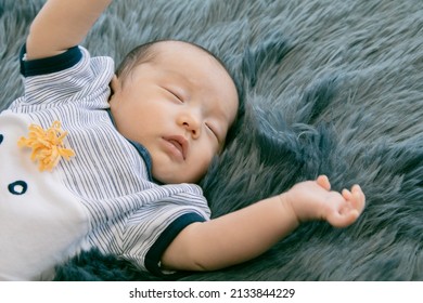 Little Newborn Baby Sleeping On Gray Fur Bed With Happy, Adorable Infant Wear Blue Casual Clothes Lying In Bedroom With Feel Safe. Asian Toddler Sleep On His Back Relaxing On Bed. Nursery For Children